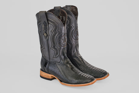 The Austin Leg - Black - Square Toe boots feature black ostrich leather, decorative stitching with a star design on the shaft, square toes, and light brown wooden soles, displayed on a light gray background.