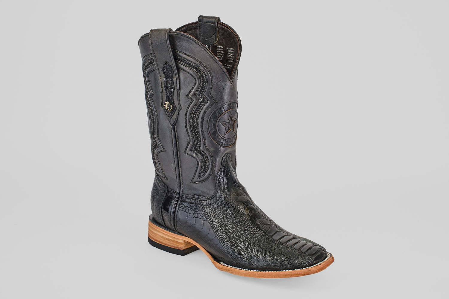 The Austin Leg - Black - Square Toe cowboy boot features detailed stitching, a star emblem, textured ostrich leather, pull straps, and a wooden sole, shown against a simple light gray background.