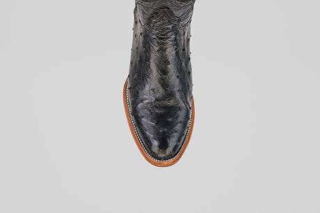 A close-up, top view of the Austin - Black - Roper Toe boot showcases its black textured ostrich leather and brown sole, highlighting refined western boot details against a plain white background.