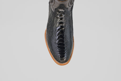 Overhead view of the Austin Leg - Black - Roper Toe boot featuring shiny black ostrich leather with a textured finish and a light brown sole, displayed on a plain light gray background.