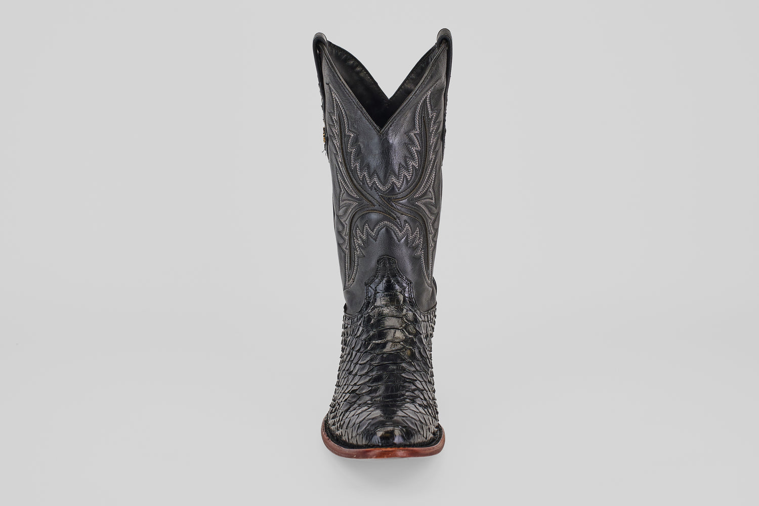 The Tanner - Black - Round Toe cowboy boot, shown front-facing on a plain light background, features intricate stitching and a textured reptile-like pattern in Python Negro Oval leather.