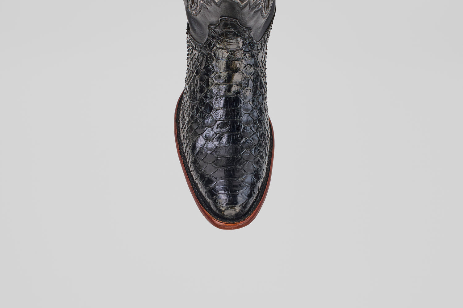 A top-down view of the Tanner - Black - Round Toe cowboy boot in textured Python Negro Oval leather with a reptile-like pattern and brown sole, set against a plain white background.