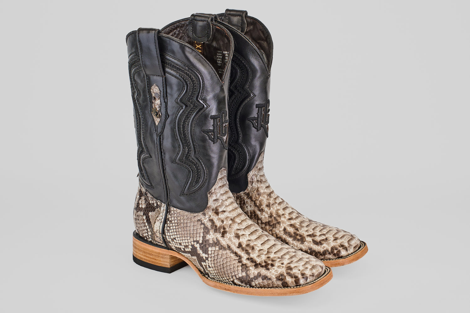The Tanner - Natural - Square Toe boots feature black leather uppers, tan Python Natural-patterned lowers, wooden heels, and decorative stitching.