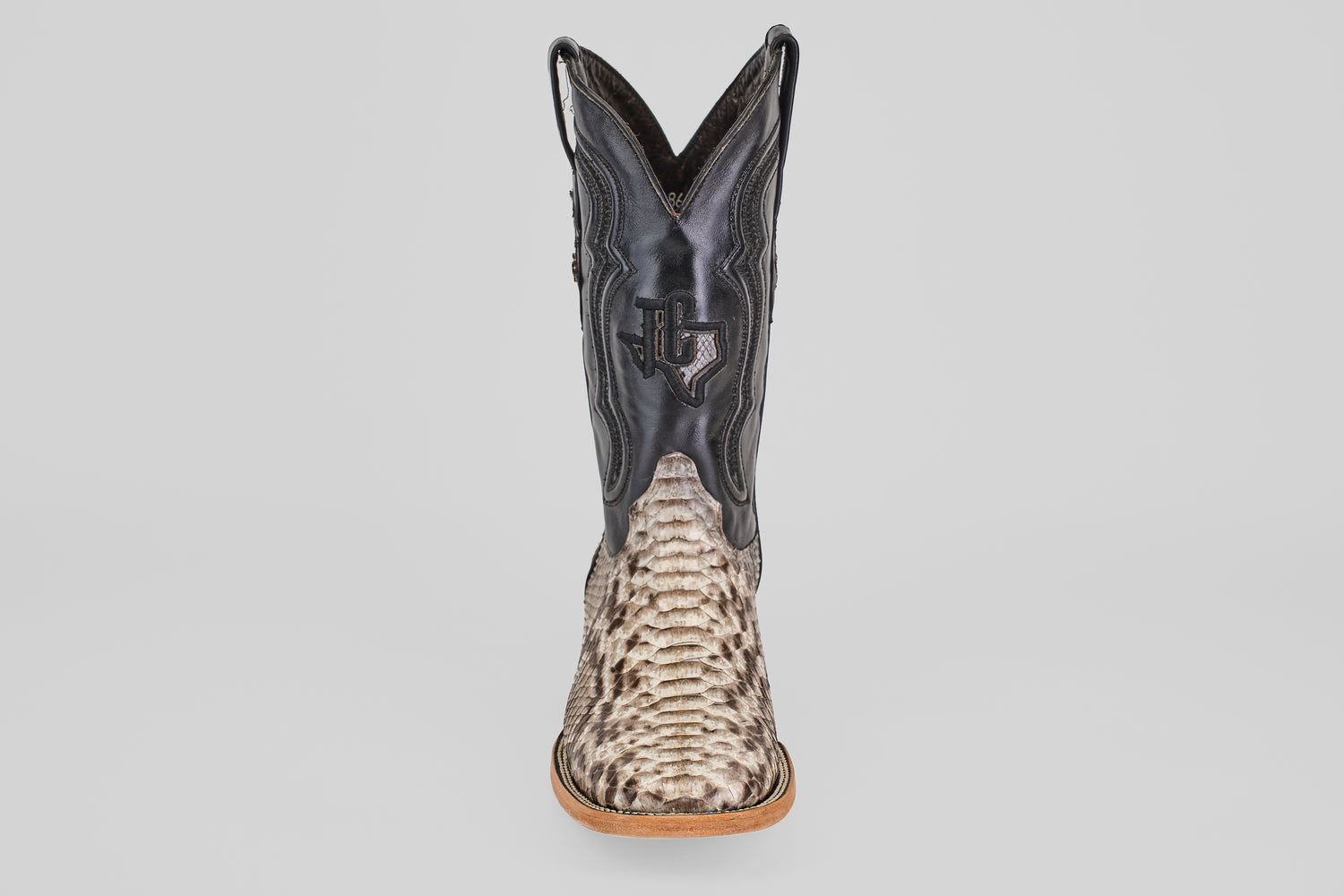 The Tanner - Natural - Square Toe cowboy boot features a textured Python Natural lower and a black leather upper with a stitched Texas outline and star, shown from the front against a plain background.