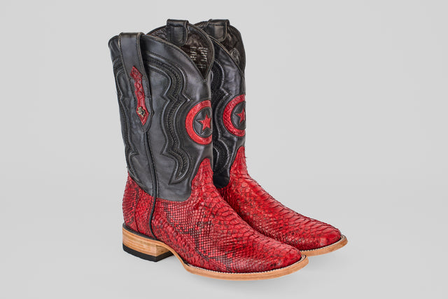 The Tanner - Ruby - Square Toe boots feature red Python Rojo snakeskin-textured lowers, black uppers with a circular star design, decorative stitching, light wooden soles, and a slight heel.