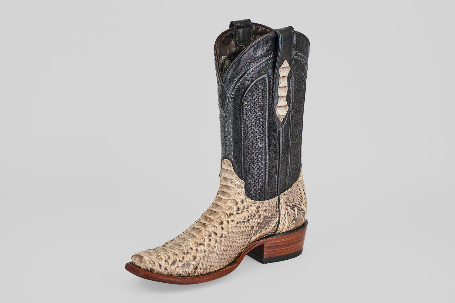 The Tanner - Natural - Narrow Square Toe cowboy boot features a black leather upper, beige snakeskin-textured lower section, narrow square toe, and wooden heel—showcasing classic Western style on a plain light background.