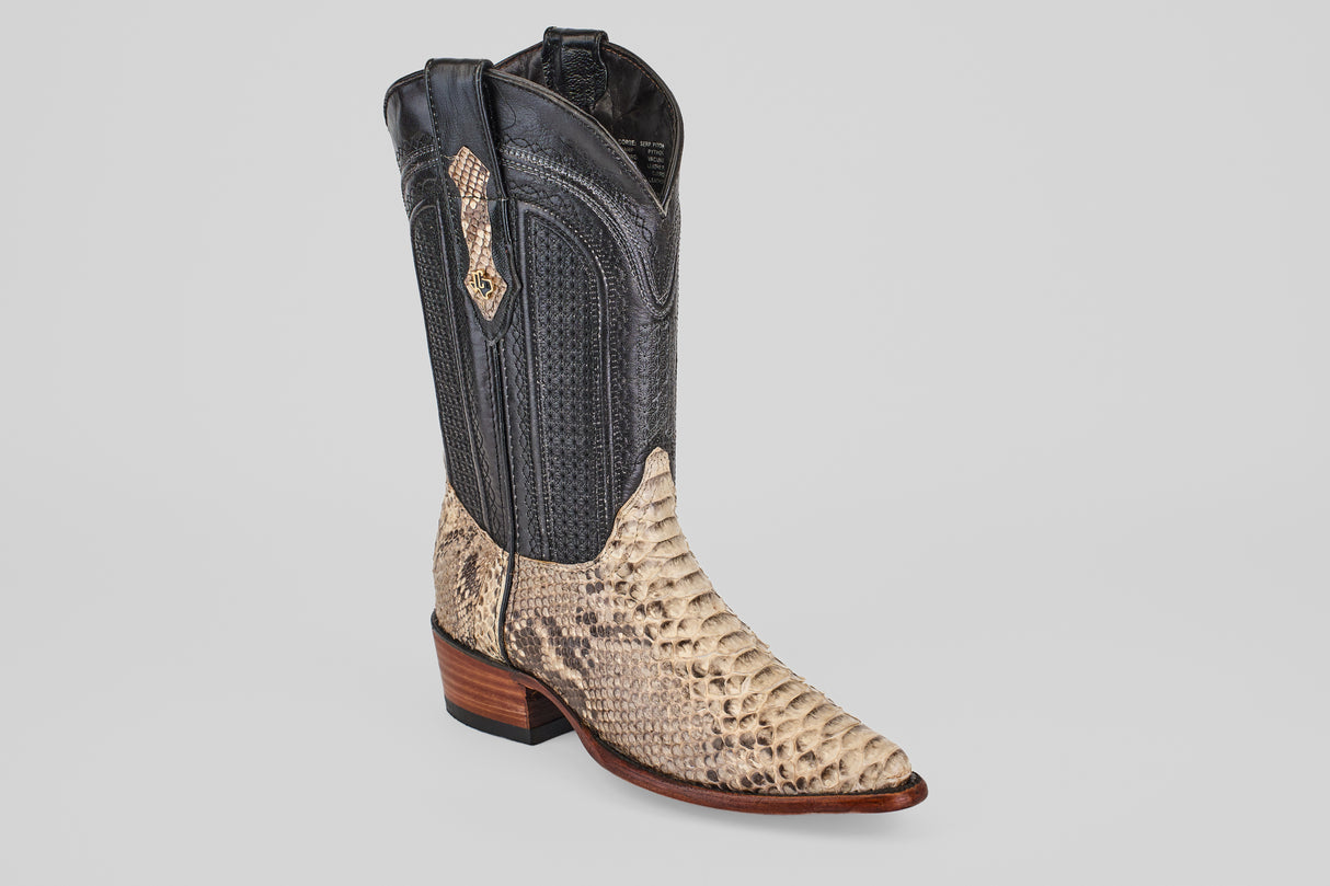 The Tanner - Natural - Snip Toe is a stylish cowboy boot with a black upper and beige python-textured lower, featuring a pointed toe and stacked wooden heel, shown on a light gray background.