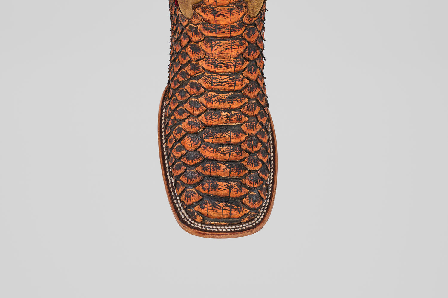 A close-up of the Tanner Jumbo – Chestnut – Square Toe boot, featuring a premium orange and black python snakeskin texture on the toe, showcased against a plain white background.