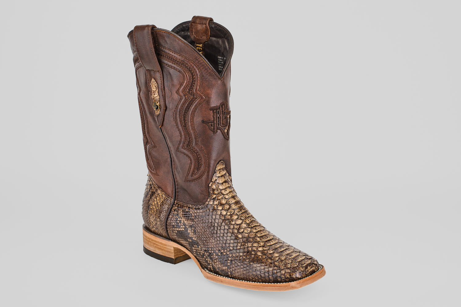 The Tanner – Dune – Square Toe boot features a brown leather upper, textured snakeskin-patterned lower section, decorative stitching, and a light wooden heel, displayed against a plain gray background.