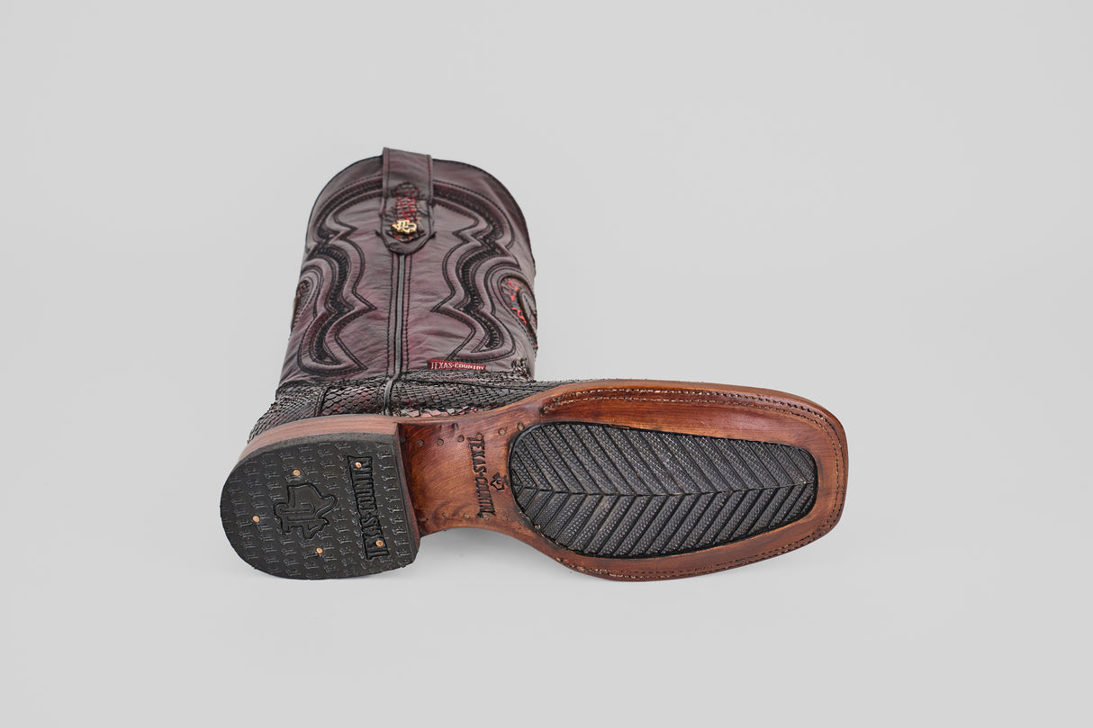 A single Tanner - Black Cherry - Square Toe boot lies on its side, showing off the dark leather upper with decorative stitching and a sole that blends leather and black rubber.