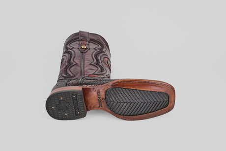 A single Tanner - Black Cherry - Square Toe boot lies on its side, showing off the dark leather upper with decorative stitching and a sole that blends leather and black rubber.