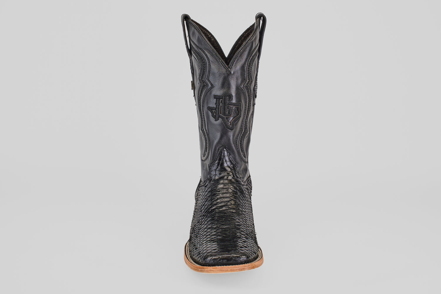 A single Tanner - Black - Square Toe cowboy boot in Python Negro leather, featuring decorative stitching and a wooden sole, is shown from the front against a plain light background.