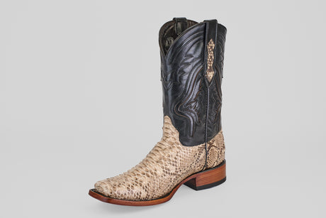 The Tanner - Natural - Rodeo Toe boot features a python natural snakeskin lower, a dark stitched leather upper, pointed toe, and wooden heel, displayed on a gray background—ideal for making a rodeo statement.