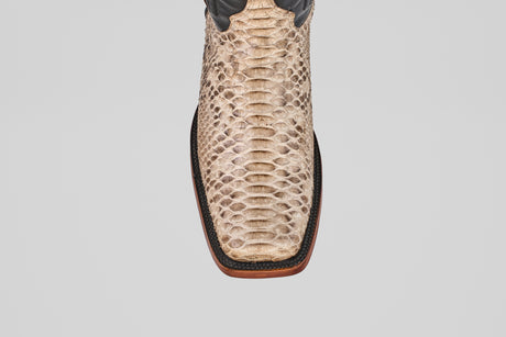 Top view of the Tanner - Natural - Rodeo Toe cowboy boot in tan natural python snakeskin, featuring a square toe, dark brown trim, and wooden sole, set against a plain light gray background.