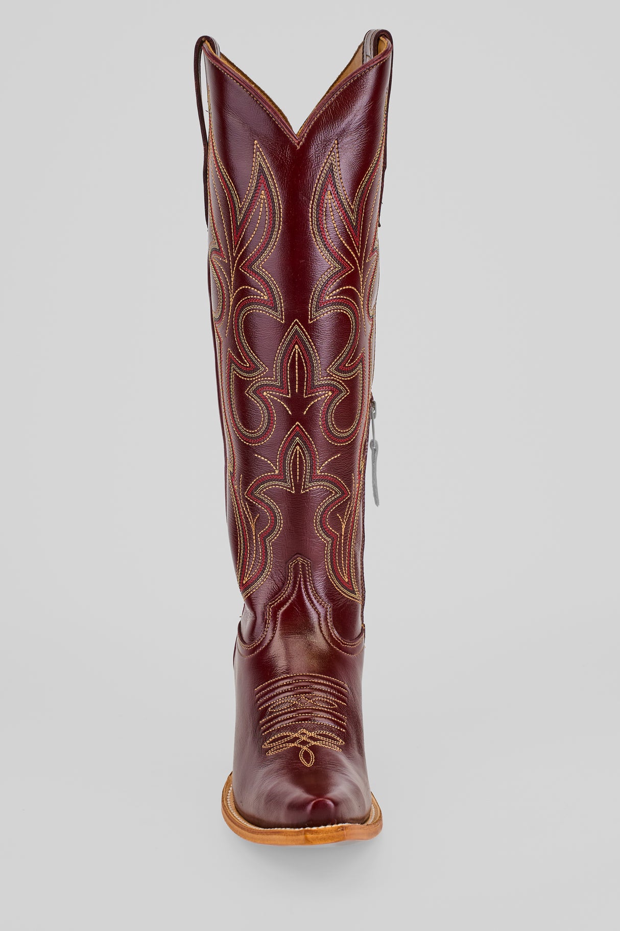 The Allison Blackberry - Tall Shaft - Snip Toe boot in dark brown features decorative stitching, a pointed toe, tan sole, and side zipper, shown upright against a gray background—ideal stylish Western boots for women.