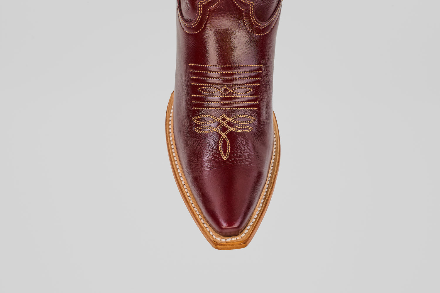 A top view of the Allison Blackberry - Tall Shaft - Snip Toe women’s Western boot, featuring a brown design with intricate yellow stitching and a tan sole, set against a plain light gray background.