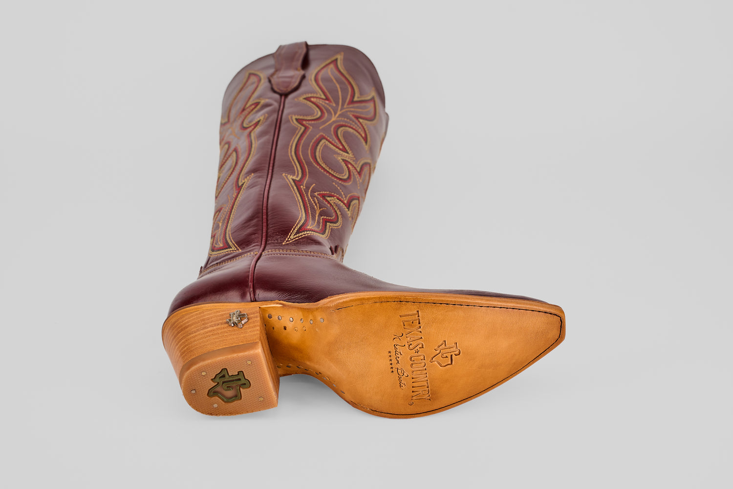 A single Allison Blackberry Tall Shaft Snip Toe boot lies on its side, showcasing decorative stitching and a green logo on the heel—classic Western boots for women. The tan leather sole is stamped with the “TX Country” logo.