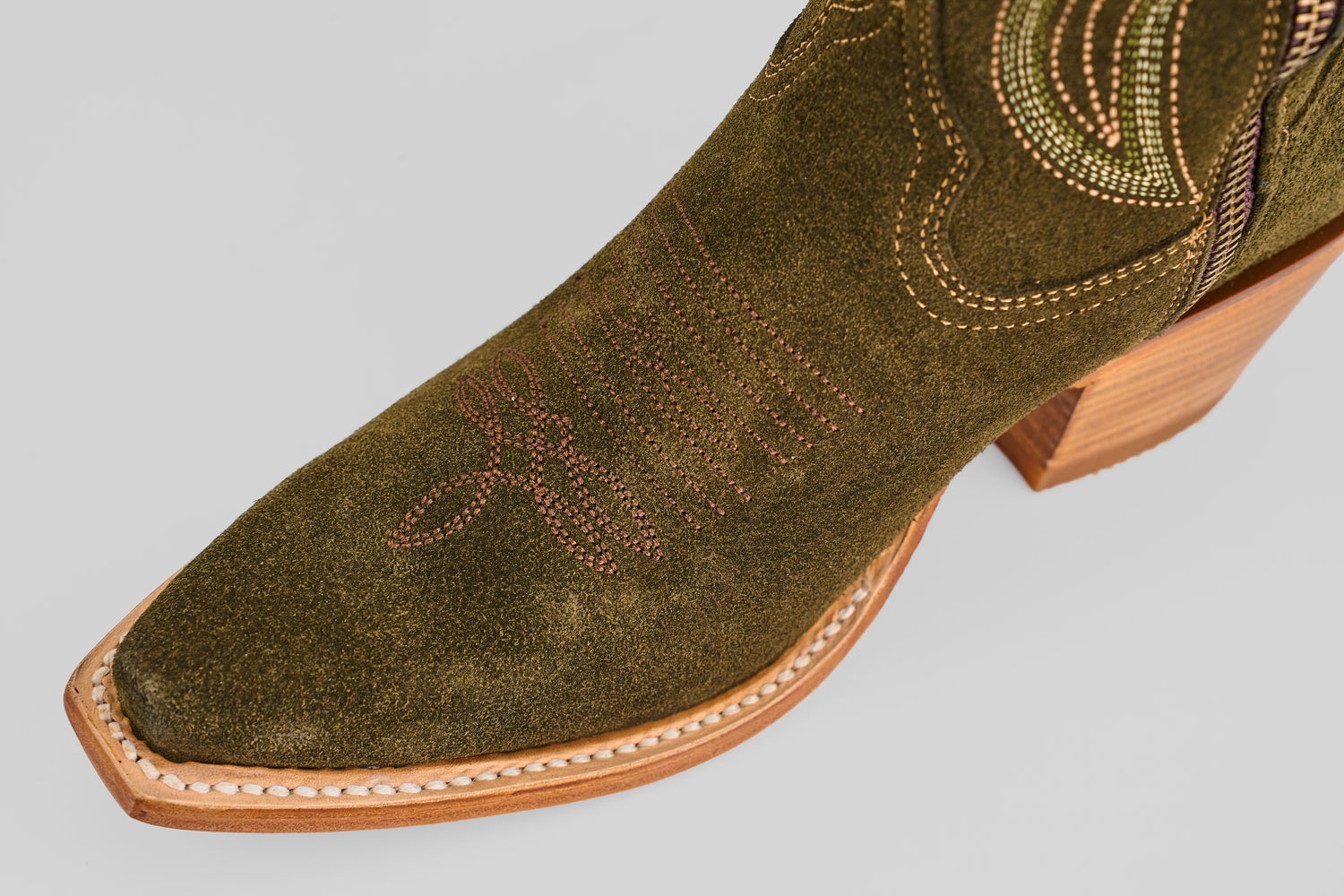 A close-up of the toe and heel of the Allison Agave - Tall Shaft - Snip Toe women’s green suede cowboy boot, featuring decorative stitching and a wooden angled heel.