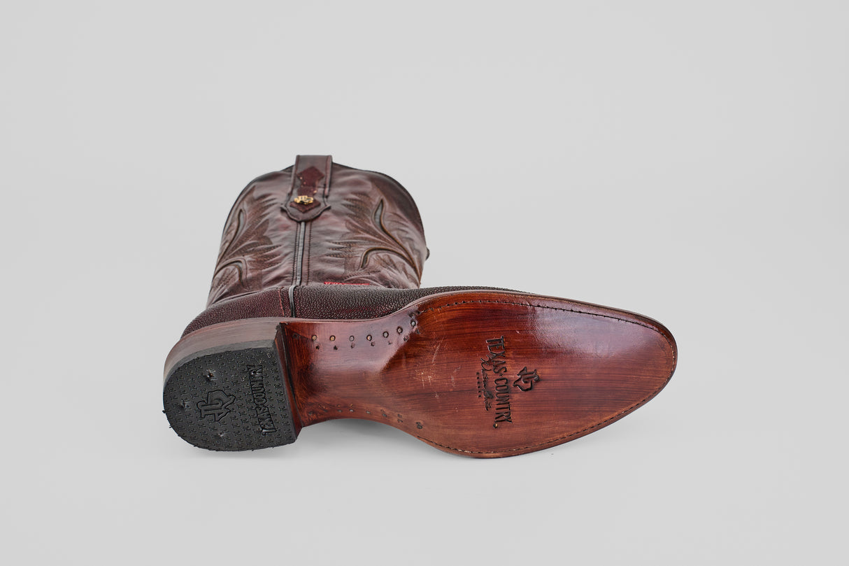 The Ranger – Wine – Round Toe men’s cowboy boot is shown on its side, featuring a smooth wooden sole with branding and a black heel, adding Western style against a plain light gray background.