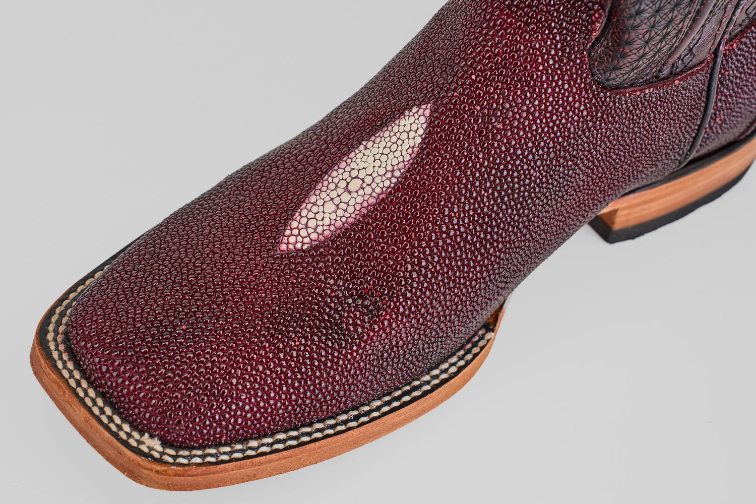 Close-up of Ranger – Wine – Square Toe boots in maroon stingray leather with a textured, pebbled surface, signature pale oval patch on top, and a light-colored stitched sole.