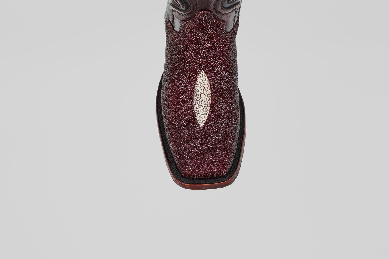 A close-up, top-down view of the Ranger – Wine – Rodeo Toe cowboy boot, showcasing its maroon stingray leather with a white diamond accent and classic rodeo toe, set against a plain light gray background.