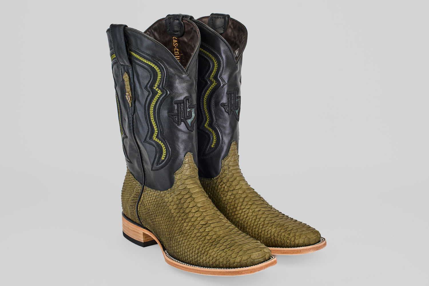 The Tanner - Green Jungle - Square Toe cowboy boots for men feature olive green textured snakeskin on the foot, light brown soles, and tall black leather shafts with yellow and green western-style stitching.