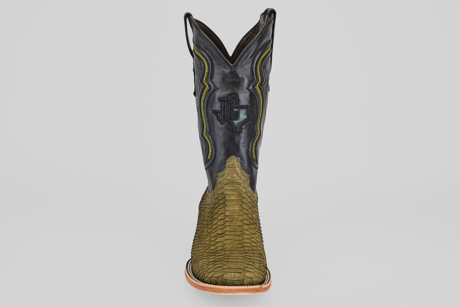 The Tanner - Green Jungle - Square Toe boot features a textured green snakeskin foot, a black leather shaft with yellow and green stitching, and classic western style, shown front-facing on a plain light background.