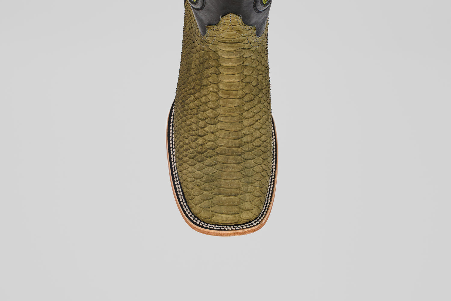 A top view of the Tanner - Green Jungle - Square Toe boot shows its olive green python leather, square toe, decorative stitching around the sole, and light brown outsole, embodying classic western style against a plain light background.