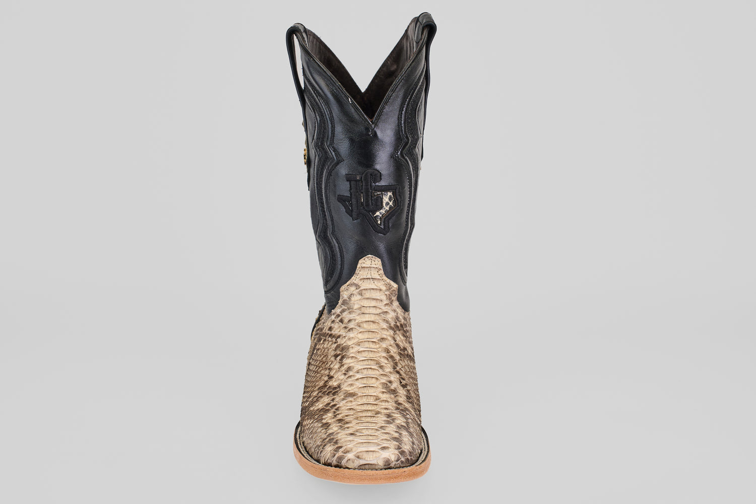 The Tanner - Matte Natural - Square Toe boot features a textured tan python leather lower, black leather upper, decorative stitching and embossing, shown from the front against a plain light gray background.