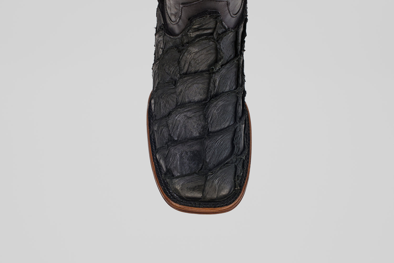 A close-up of the toe of the Conor Platinum - Matte Black - Square Toe (Diamond) boot, featuring black textured material with brown edge stitching—rugged and patterned for a distinctive western style.
