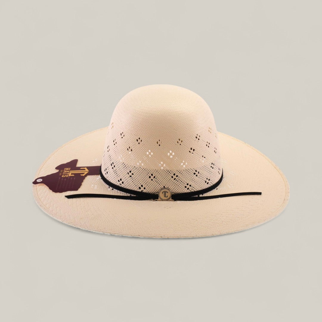 A light-colored, wide-brimmed 30X Clover - Open Crown straw hat featuring diamond cutouts, a black band with a gold circular emblem, and a brown tag—elegantly displayed on a neutral background.