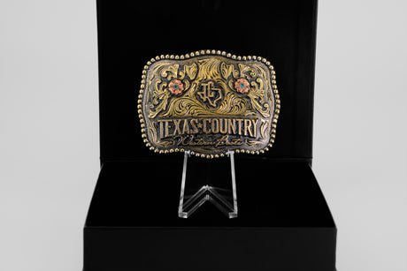 The Texas Country Buckle - Mod 3 features floral designs and gold accents, displayed upright in a black box—an eye-catching piece ideal for Western belt buckle collectors.