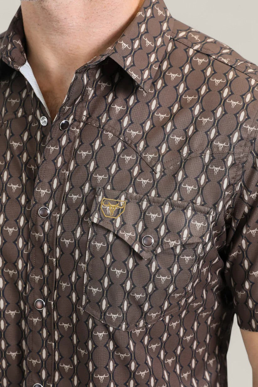 A close-up of a person wearing the Mens Performance Western Short Sleeve Aztec Print Brown Shirt (PGW10643), featuring a chest pocket and an Aztec pattern that blends modern style with classic Western wear.