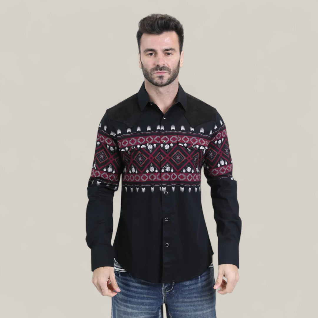 A man wears the Mens Western Modern Fit Cotton/Spandex Long Sleeve Black Shirt with Snaps (WPL10750), featuring red and white geometric patterns, paired with blue jeans, standing against a plain light grey background.