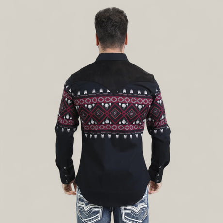 A man faces away from the camera, wearing the Mens Western Modern Fit Cotton/Spandex Long Sleeve Black Shirt with Snaps (WPL10750) featuring a red, white, and purple geometric pattern on the back and sleeves, paired with light jeans. The background is beige.