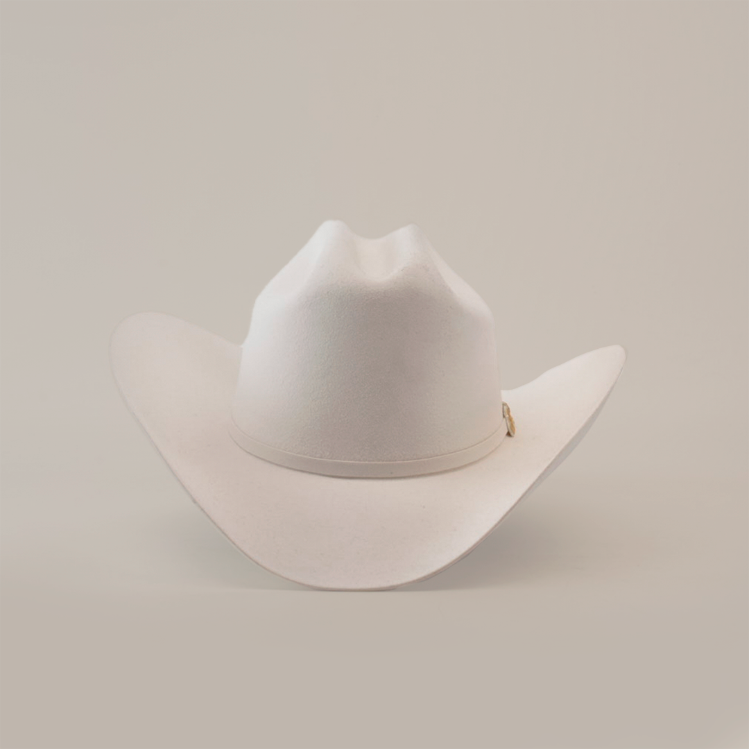 The 6X Real White is a luxury Western cowboy hat with a wide brim and creased crown, handcrafted by artisans from fur felt. It is elegantly displayed against a plain white background.