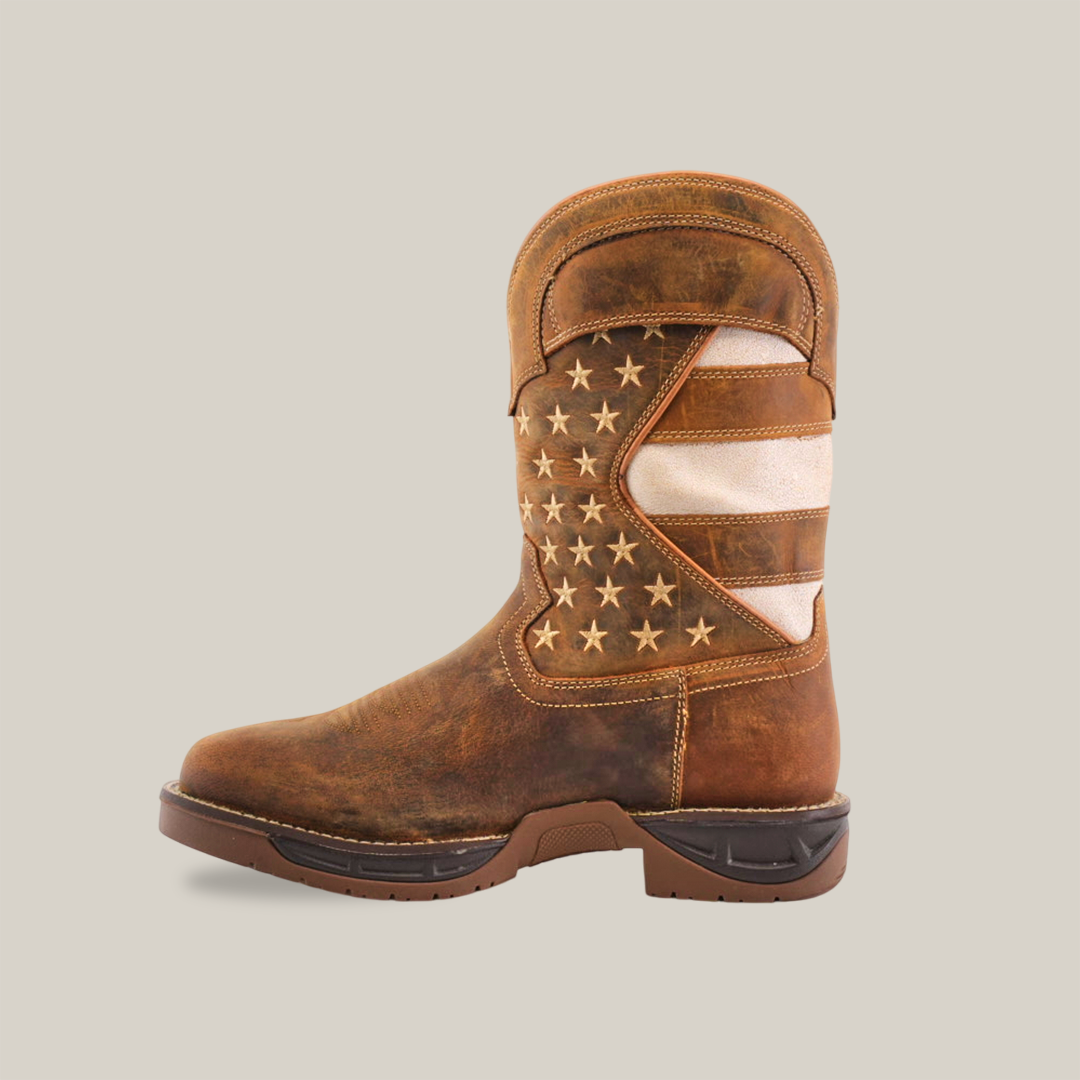 The White Tan US Flag boot is a handcrafted, waterproof leather boot with an American flag design featuring white stars on blue and red and white stripes. It boasts a rugged, worn look with a thick sole and soft toe.