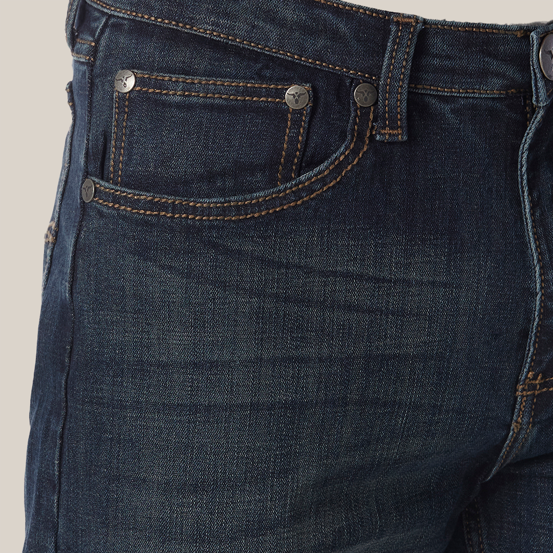 Close-up of a person wearing Wrangler 20X No. 33 Extreme Appleby Dark Wash Relaxed Straight Leg Jean, featuring visible stitching and metal rivets. The premium denim with a classic five-pocket design pairs perfectly with a light grey top.