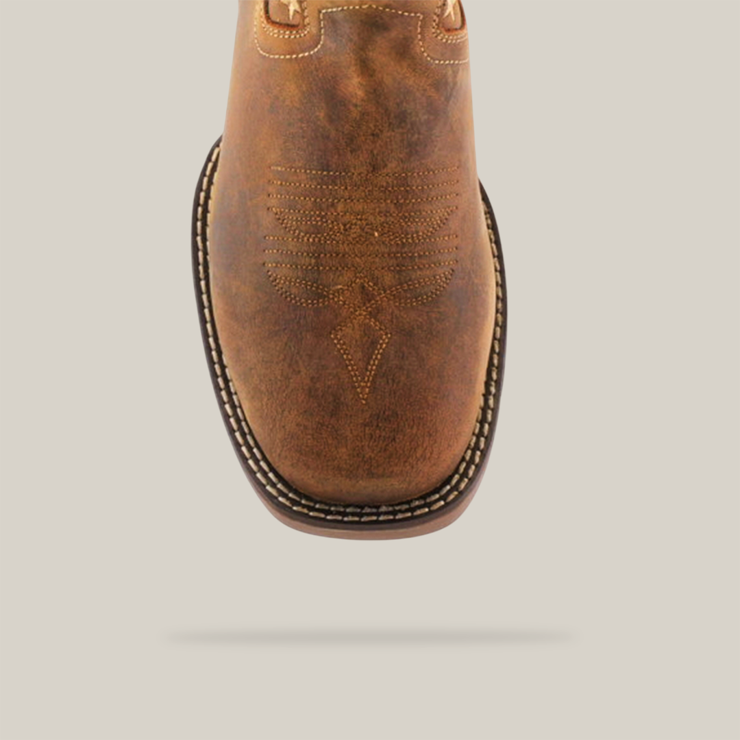 Close-up of the White Tan US Flag cowboy boot, handcrafted with decorative stitching on the toe. This waterproof, soft-toe boot has a square toe design and a black and white stitched welt. Made from cowhide leather, it boasts a worn finish for an appealing vintage look.