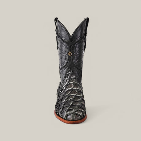 The Exotic Pirarucu Fish - Newspaper - Roper Toe is a luxurious black cowboy boot made from textured Pirarucu leather, showcasing intricate stitching and a front emblem, elegantly standing against a plain gray background.