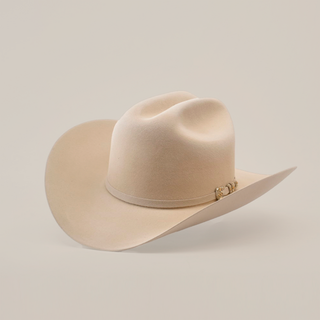 The 10X Jerarca Belly is a cream-colored cowboy hat made from luxurious fur felt, featuring a wide brim and distinctive crown crease. Adorned with a decorative metallic embellished band, this classic western headwear evokes Larry Mahans timeless style against a white backdrop.