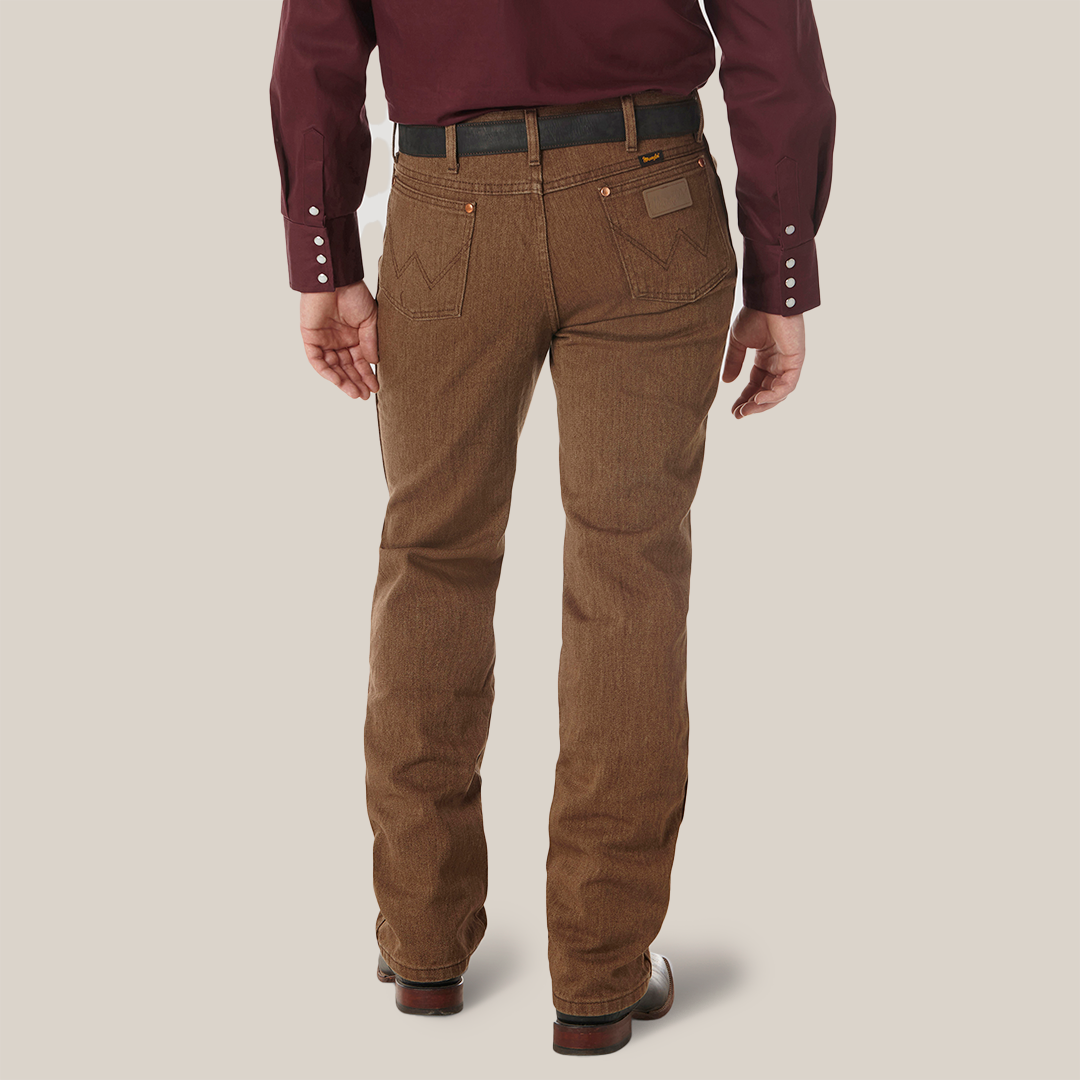 A person in a maroon long-sleeve shirt and brown Wrangler Cowboy Cut Slim Fit Jean - 100936BKW stands with their back to the camera, hands at their sides. The pants have pockets, and the shirts buttoned cuffs perfectly complement the brown shoes.