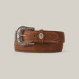 The Tan Plain Belt - Rustic Buckle is a tan leather belt with intricate floral patterns on the buckle, neatly coiled with visible stitching along the edges, set against a plain gray background.