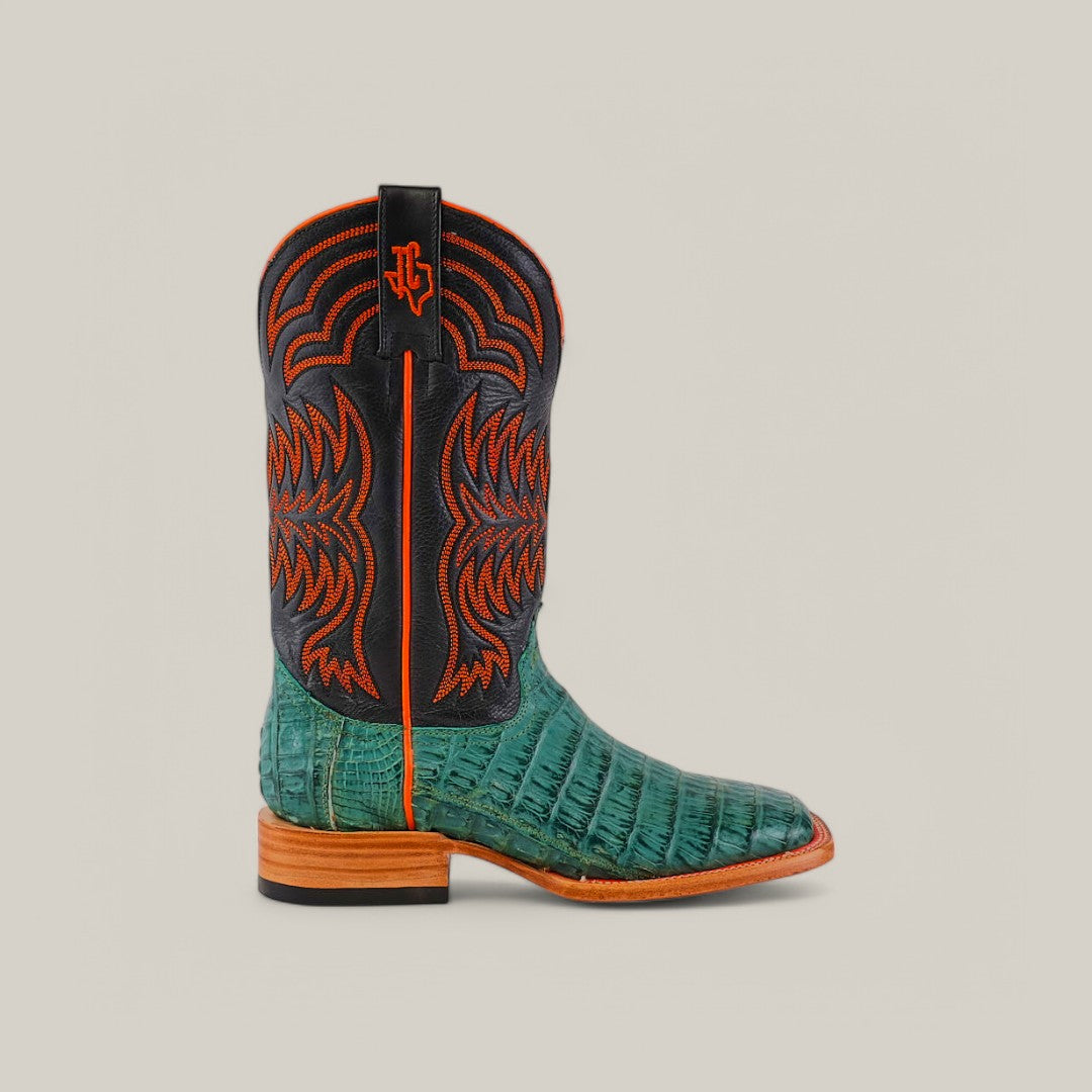 The Exotic Caiman Belly Tail cowboy boot, featuring a teal alligator skin lower from premium caiman leather and a black shaft with red stitching, showcases a wooden heel against a neutral background.