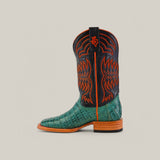 The Exotic Caiman Belly Tail - Green boot features premium caiman leather with an alligator texture, a black shaft with orange stitching and logo, a wooden heel, and pull-tab, all set against a plain light gray background.