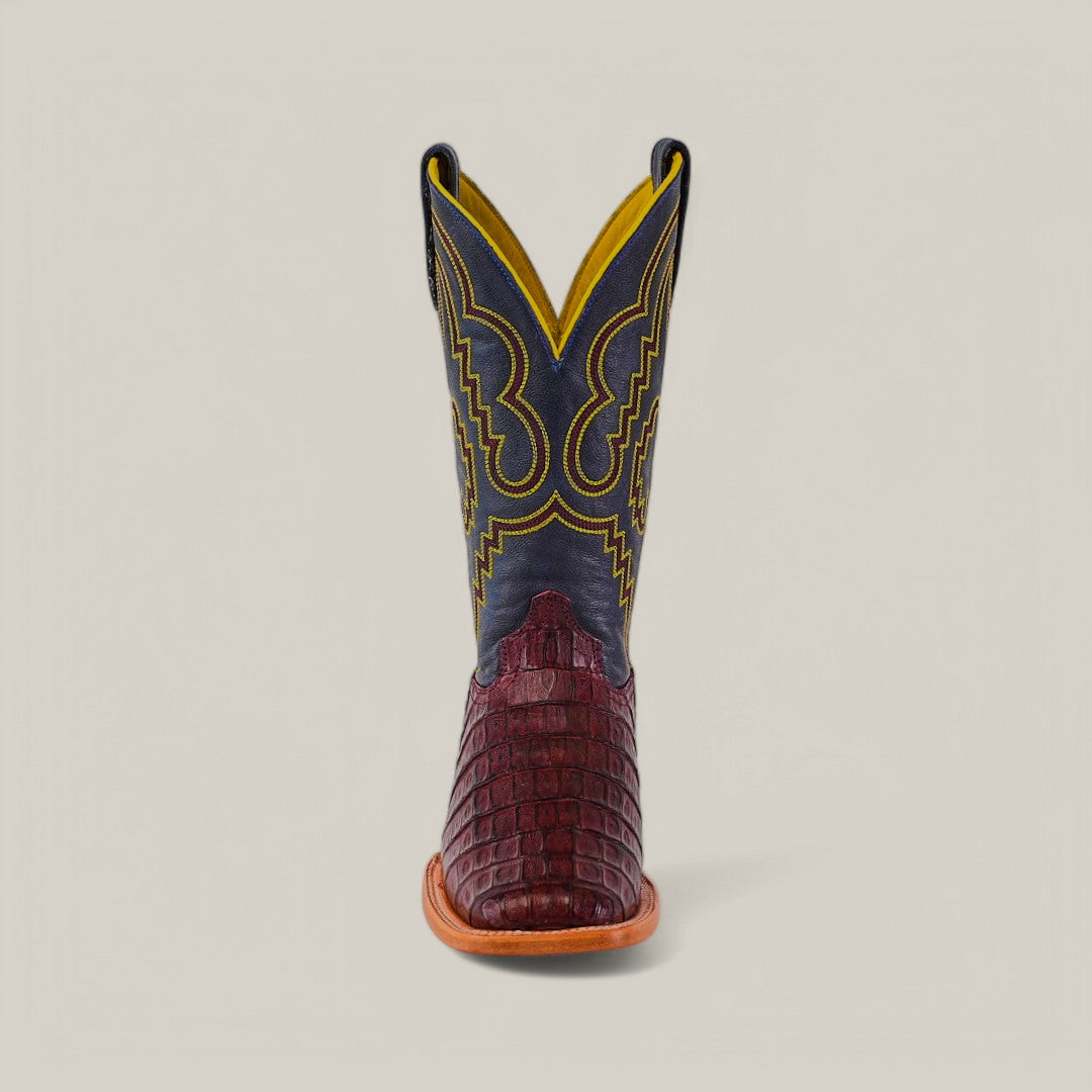 The Exotic Caiman Belly Tail boot in Wine features a square toe, brown crocodile-textured foot, dark upper shaft with intricate yellow stitching, showcased against a plain background for added flair.