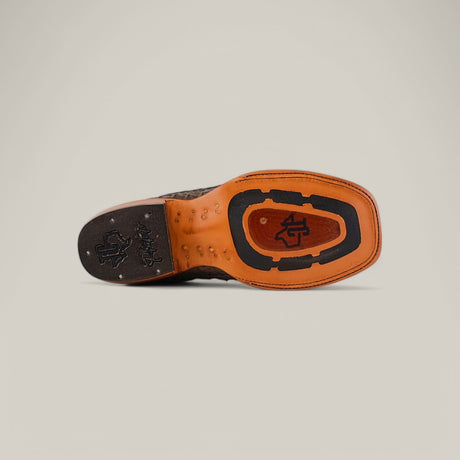 The image reveals the sole of an Exotic Caiman Belly Tail shoe, Gray with a Square Toe, featuring a unique Western-style pattern. The textured grooves, stylized logo initials, and contrasting tan and black colors highlight the refined craftsmanship typical of exotic leather designs.