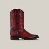 The Wyatt - Cogñac - Roper Toe is a single red leather cowboy boot with decorative stitching, a low heel, and pull strap, shown in side profile against a plain beige background.