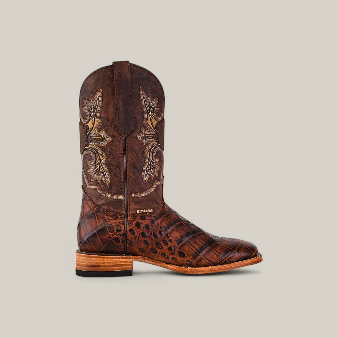 The Jonh - Brown - Square Toe cowboy boot features intricate shaft stitching and a textured, alligator-style premium leather lower, highlighting quality craftsmanship against a plain light background.