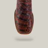 A close-up of Jonh - Brown - Square Toe premium leather boots showcases an alligator pattern, quality craftsmanship, and intricate stitching along the square toe, set against a plain beige background.